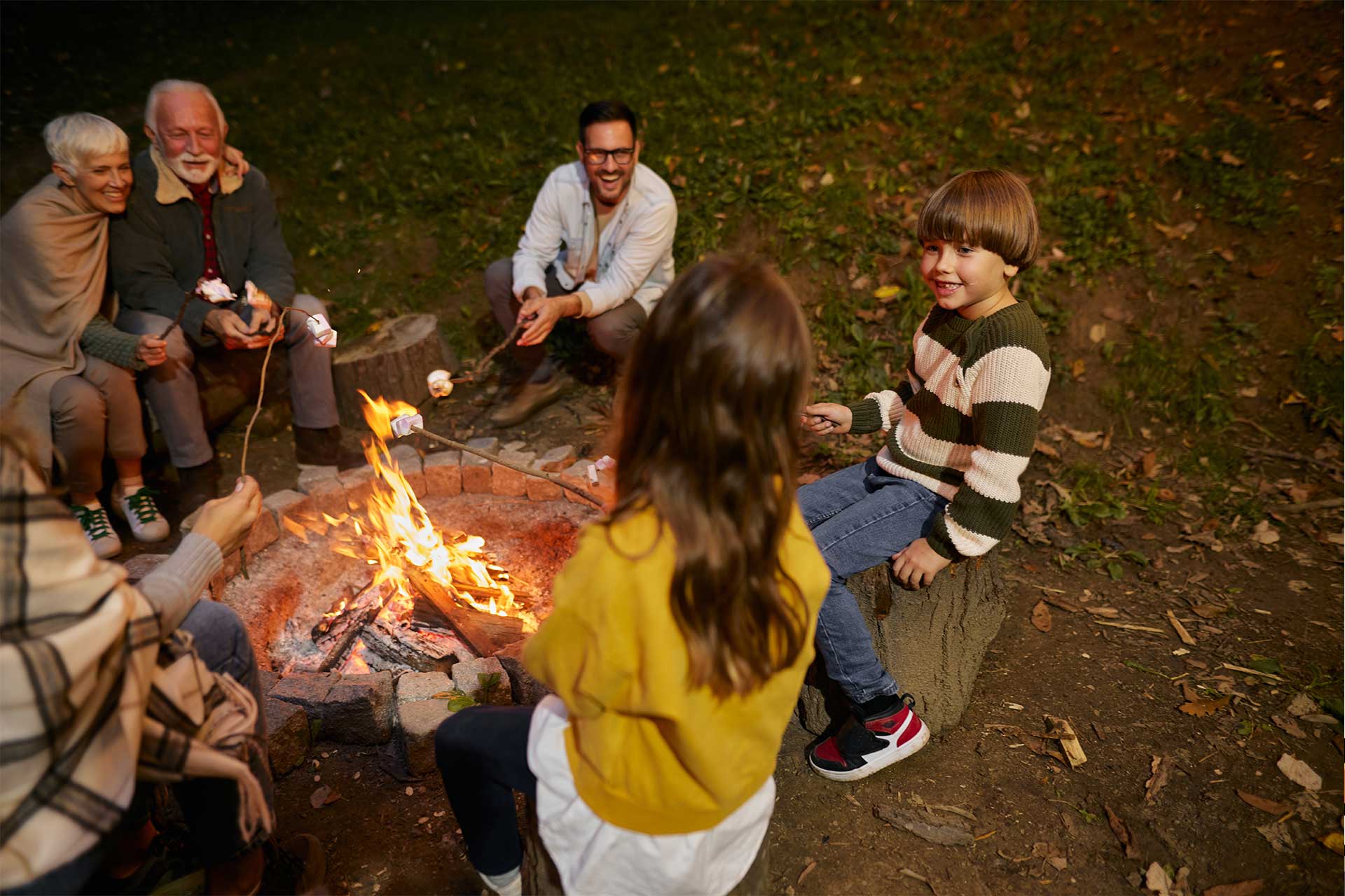 Family enjoying a campfire and roasting marshmallows, thanks to Pro Mosquito Solutions natural, eco-friendly mosquito and tick control.