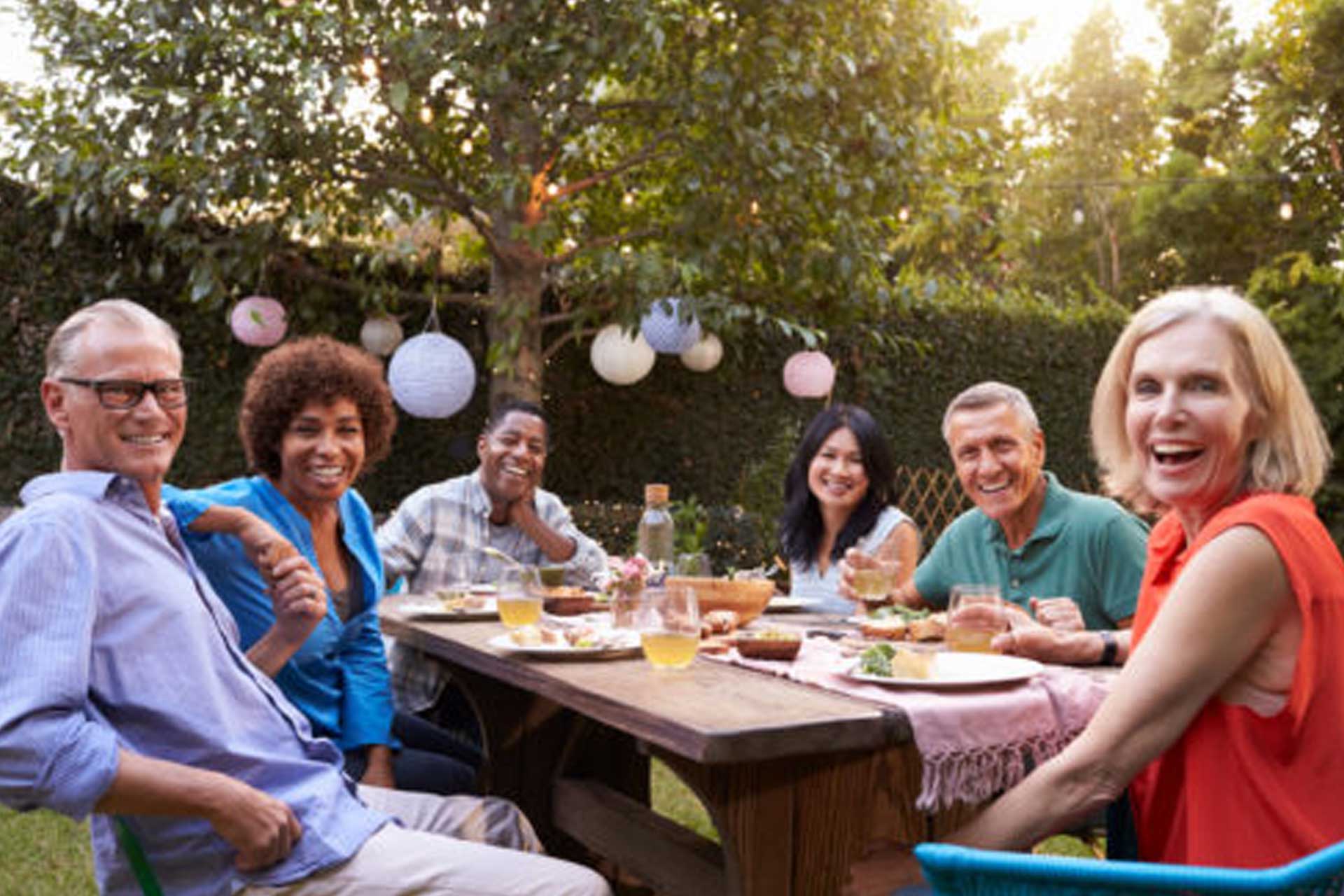 Family laughing and enjoying their backyard while sitting at a table, celebrating a special event in a mosquito- and tick-free environment, made possible by Pro Mosquito Solutions.