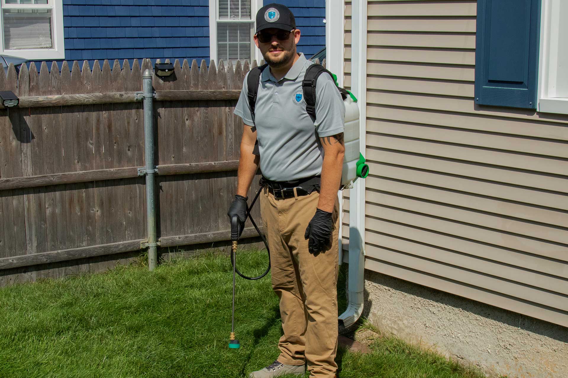 Pro Mosquito Solutions technician in uniform with a professional foundation sprayer, preparing to apply a thorough foundation barrier treatment for effective pest control in Rhode Island.
