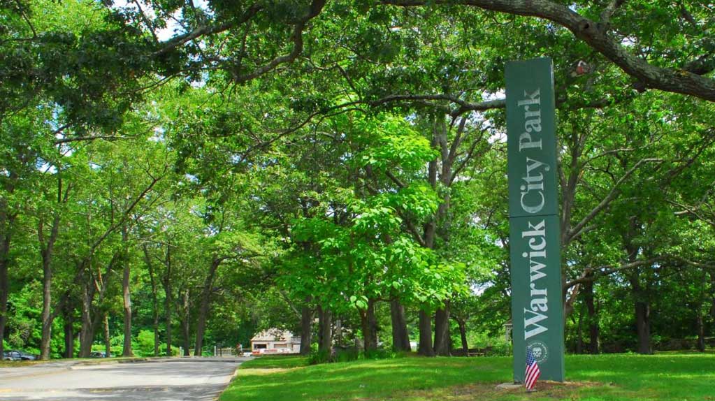 Scenic view of Warwick City Park with lush greenery, a serene waterfront, and walking paths, providing a tranquil outdoor experience in Rhode Island.