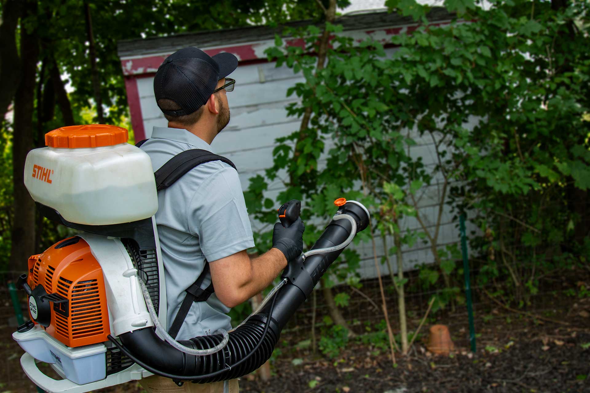 Pro Mosquito Solutions technician spraying a yard for mosquito and tick control, using professional equipment to protect the outdoor space from pests.