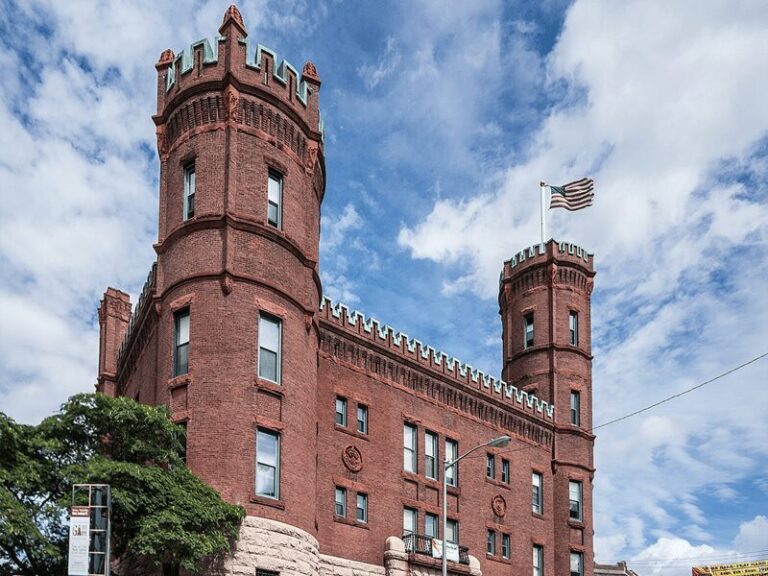 The Pawtucket Armory Arts Center, a historic brick building with a castle-like facade, tall towers, and arched windows, serving as a cultural hub in Pawtucket, RI.