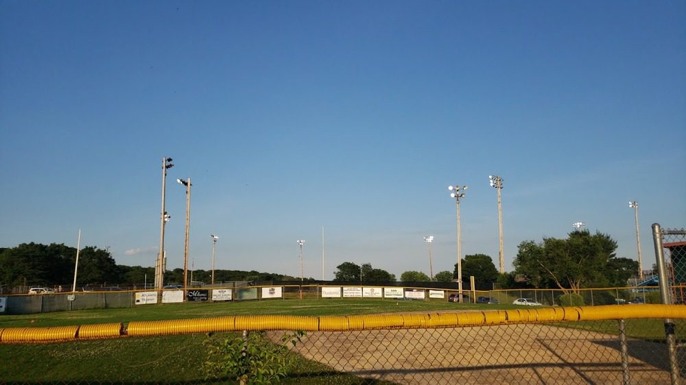 Baseball field at Riverpoint Park in West Warwick, RI, surrounded by lush green spaces and trees.