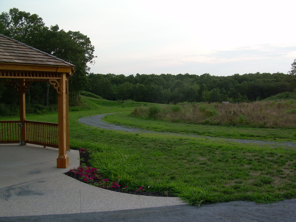 Seekonk Meadows Park in Seekonk, MA, featuring lush green fields, scenic walking trails, and a serene pond under a bright blue sky.