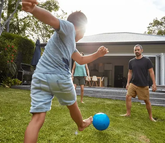 Father and son playing soccer in a family-safe, mosquito and tick-free backyard, created by Pro Mosquito Solutions outdoor pest control in Rhode Island and Southeastern Massachusetts.