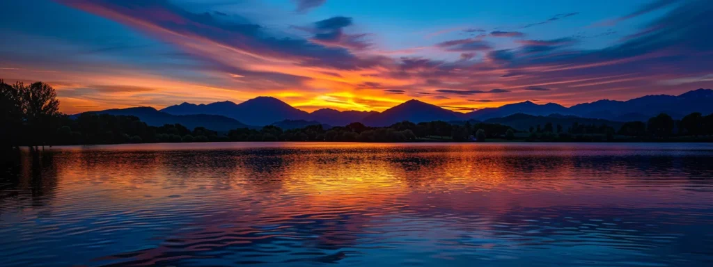 a vibrant sunset casts a golden glow over a tranquil lake, with dramatic mountains silhouetted against the colorful sky, creating a serene yet captivating natural wonder.