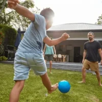Father and son playing soccer in a family-safe, mosquito and tick-free backyard, created by Pro Mosquito Solutions outdoor pest control in Rhode Island and Southeastern Massachusetts.