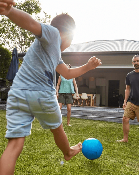 A man and a boy play soccer in a mosquito-free backyard in Rhode Island, enjoying family fun in a pest-controlled outdoor space by Pro Mosquito Solutions.